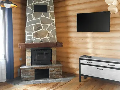 a living room with a stone fireplace with a flat screen tv at Власовъ in Pamporovo