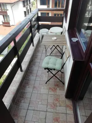 a patio with a table and a chair on a balcony at апартамент Гигови in Bansko