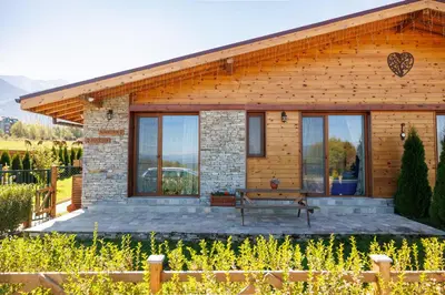 a wooden house with a bench in front of it at Mountain villa Aleksia- with JACUZZI in Razlog