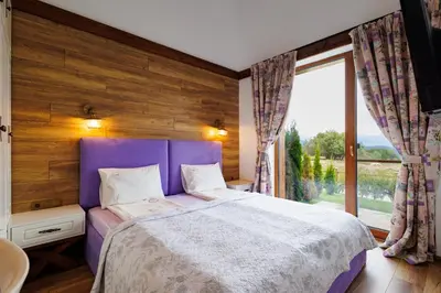 a bedroom with a purple bed and a large window at Mountain villa Aleksia- with JACUZZI in Razlog