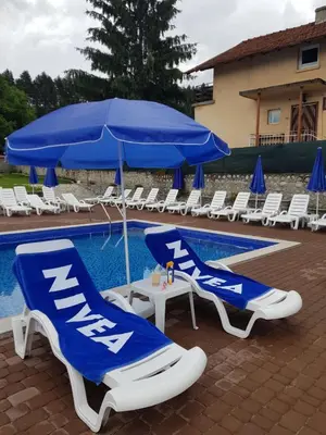 two blue and white chairs and an umbrella next to a pool at Семеен Хотел-