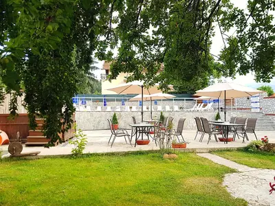 a patio with tables and chairs and umbrellas at Семеен Хотел-
