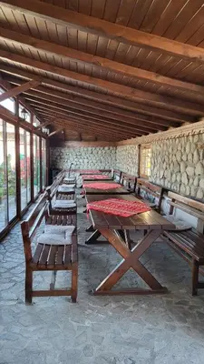 a row of wooden tables in a room with windows at Семеен Хотел-