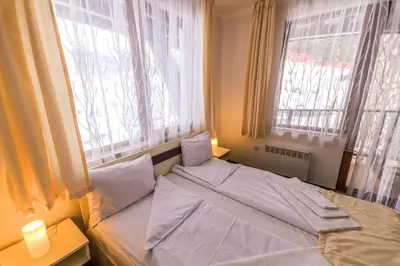 a bed in a room with two windows at Grand Monastery Violet Apartment With One Bedroom And A Terrace in Pamporovo