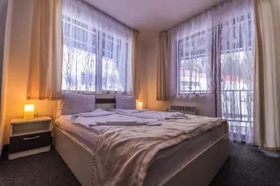 a bedroom with a large bed with two windows at Grand Monastery Violet Apartment With One Bedroom And A Terrace in Pamporovo
