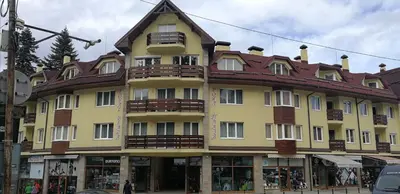 a large yellow building with a brown roof at BOROVETS Royal Plaza - A409 in Borovets