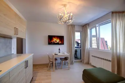 a kitchen with a table with a fire on the wall at Pinewood Apartment Borovets in Borovets