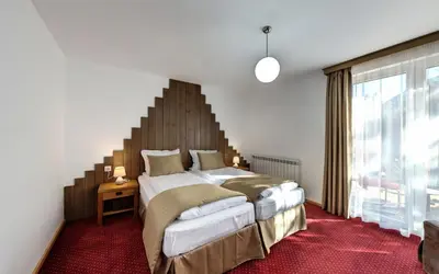 a bedroom with two beds and a large window at ШАЛЕТ БЕАТРИС in Razlog