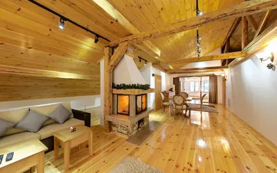 a living room with a fireplace and wooden ceilings at ШАЛЕТ БЕАТРИС in Razlog