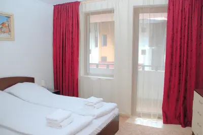 a bedroom with a bed with red curtains and a window at Гранд Манастира Апартаменти 