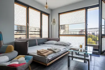 a bedroom with a bed and a table and windows at Boutique 1-bedroom flat in the heart of the city in Plovdiv