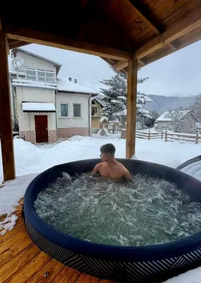 a boy sitting in a hot tub in the snow at Мальовица - къща за гости in Dospey Makhala