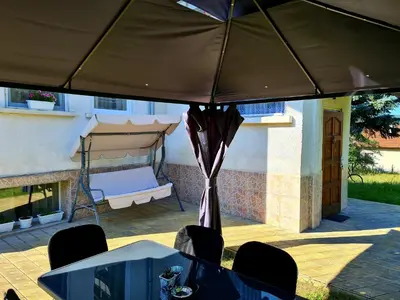 a table and chairs under a large umbrella at Мальовица - къща за гости in Dospey Makhala