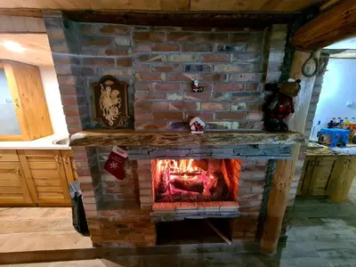 a brick fireplace in the middle of a kitchen at Мальовица - къща за гости in Dospey Makhala