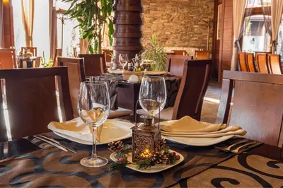a table in a restaurant with wine glasses on it at Хотел Том и Нези Класик in Velingrad