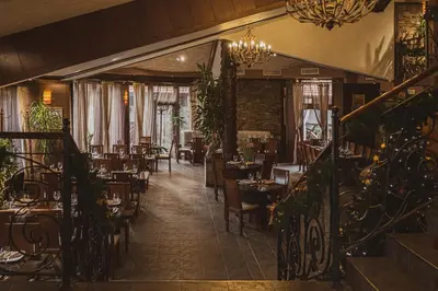 a restaurant with tables and chairs and a chandelier at Хотел Том и Нези Класик in Velingrad