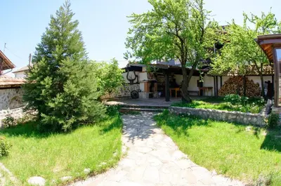 a house with a yard with a tree and a walkway at Self Catering Chalet Kulina in Bansko