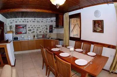 a kitchen and dining room with a wooden table and chairs at Self Catering Chalet Kulina in Bansko