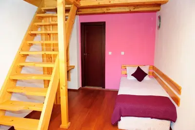 a bedroom with a bunk bed and a wooden staircase at Self Catering Chalet Kulina in Bansko