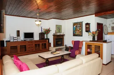 a living room with a white couch and a fireplace at Self Catering Chalet Kulina in Bansko