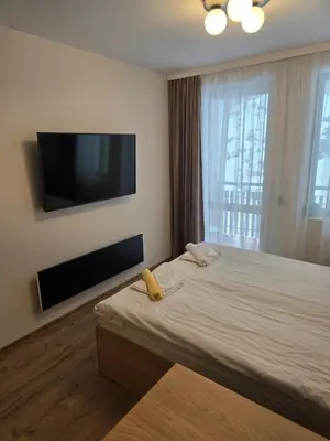 a bedroom with a large bed with a flat screen tv at Студио Пампорово Палас - Pamporovo Palace in Pamporovo