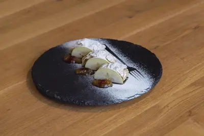 a black plate with food on a wooden table at Hotel COTA1110 in Beli Iskar