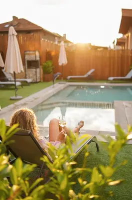 a woman laying in a chair next to a swimming pool at Guest house Wishmore in Banya