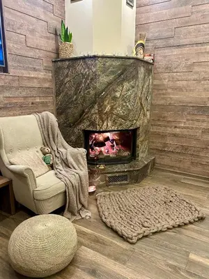 a living room with a fireplace and a chair at Къща за гости Амая - Сандански in Sandanski