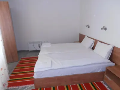 a bedroom with a bed with white sheets and a rug at Monastery 3 Apartments TMF in Pamporovo