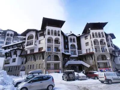 a large building with cars parked in the snow at Monastery 3 Apartments TMF in Pamporovo