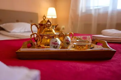 a tray with a tea kettle and cups on a bed at Family Hotel Chichin in Bansko