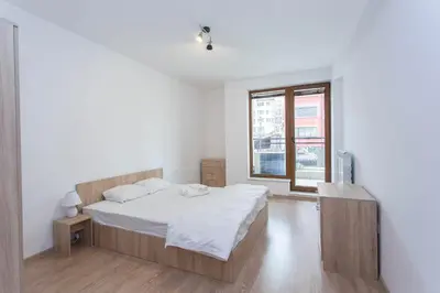 a white bedroom with a bed and a window at Modern and Bright Apartments near Center - FREE PARKING in Sofia