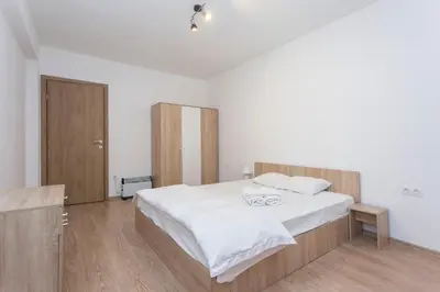 a bedroom with a large white bed and wooden floors at Modern and Bright Apartments near Center - FREE PARKING in Sofia