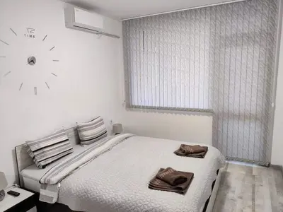a bedroom with a bed with a clock on the wall at Apartment Anelia 3 in Plovdiv