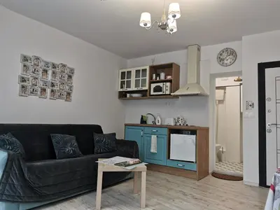 a living room with a black couch and a kitchen at Retro Studio byPMM in Plovdiv