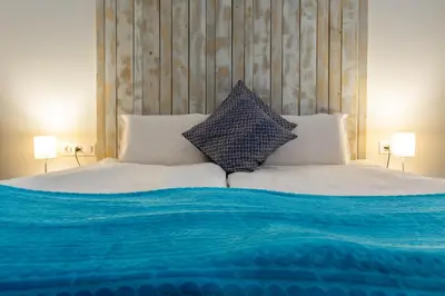 a bed with blue and white sheets and pillows at Къщи за гости Сноуфлейк Snowflake Chalet and Snowflake Lodge in Bansko