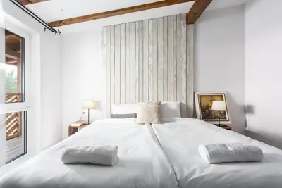 a white bedroom with a large white bed with two pillows at Къщи за гости Сноуфлейк Snowflake Chalet and Snowflake Lodge in Bansko