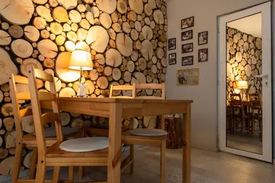 a room with a table and chairs and a wall of logs at Къщи за гости Сноуфлейк Snowflake Chalet and Snowflake Lodge in Bansko