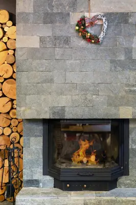 a fireplace with a stone wall with a fire at Къщи за гости Сноуфлейк Snowflake Chalet and Snowflake Lodge in Bansko