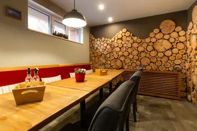 a dining room with a wooden table and some bottles of wine at Къщи за гости Сноуфлейк Snowflake Chalet and Snowflake Lodge in Bansko