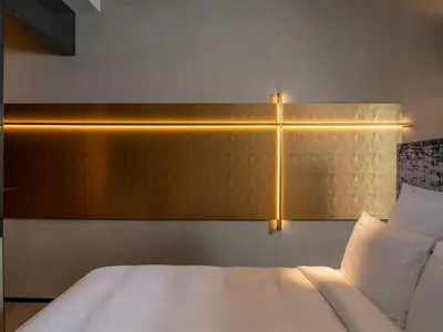 a bedroom with a white bed with a gold headboard at The Emporium Hotel Plovdiv - MGallery Collection in Plovdiv