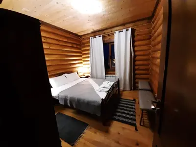 a bedroom with a bed in a wooden room at къщи за гости Под звездите in Pamporovo