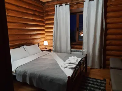 a bed in a wooden room with a window at къщи за гости Под звездите in Pamporovo