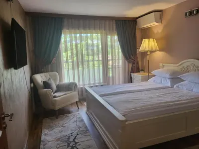 a bedroom with a bed and a chair and a window at Студио Лидия in Velingrad