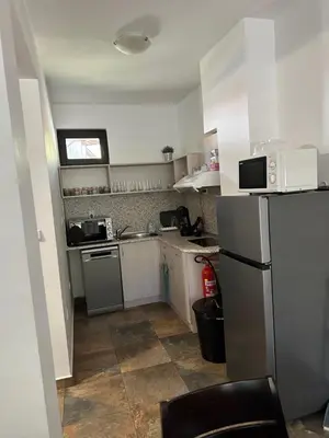 a small kitchen with white cabinets and a refrigerator at Марковската къща in Oreshak