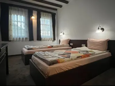 two beds sitting in a room with windows at Galabova Guesthouse in Delchevo