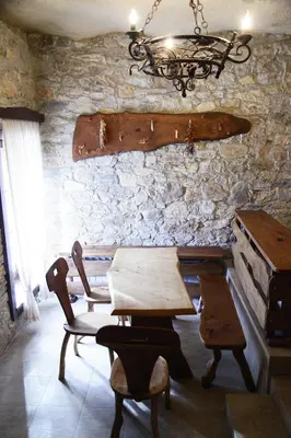 a table and chairs in a room with a stone wall at Galabova Guesthouse in Delchevo