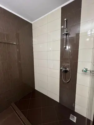a bathroom with a shower with brown and white tiles at Galabova Guesthouse in Delchevo