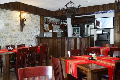 a restaurant with wooden tables and chairs and a bar at Galabova Guesthouse in Delchevo