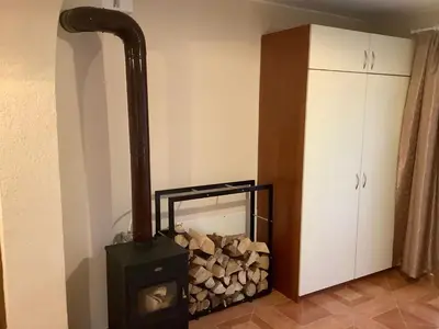 a wood stove in a room with a pile of wood at Приключение в Триград in Trigrad